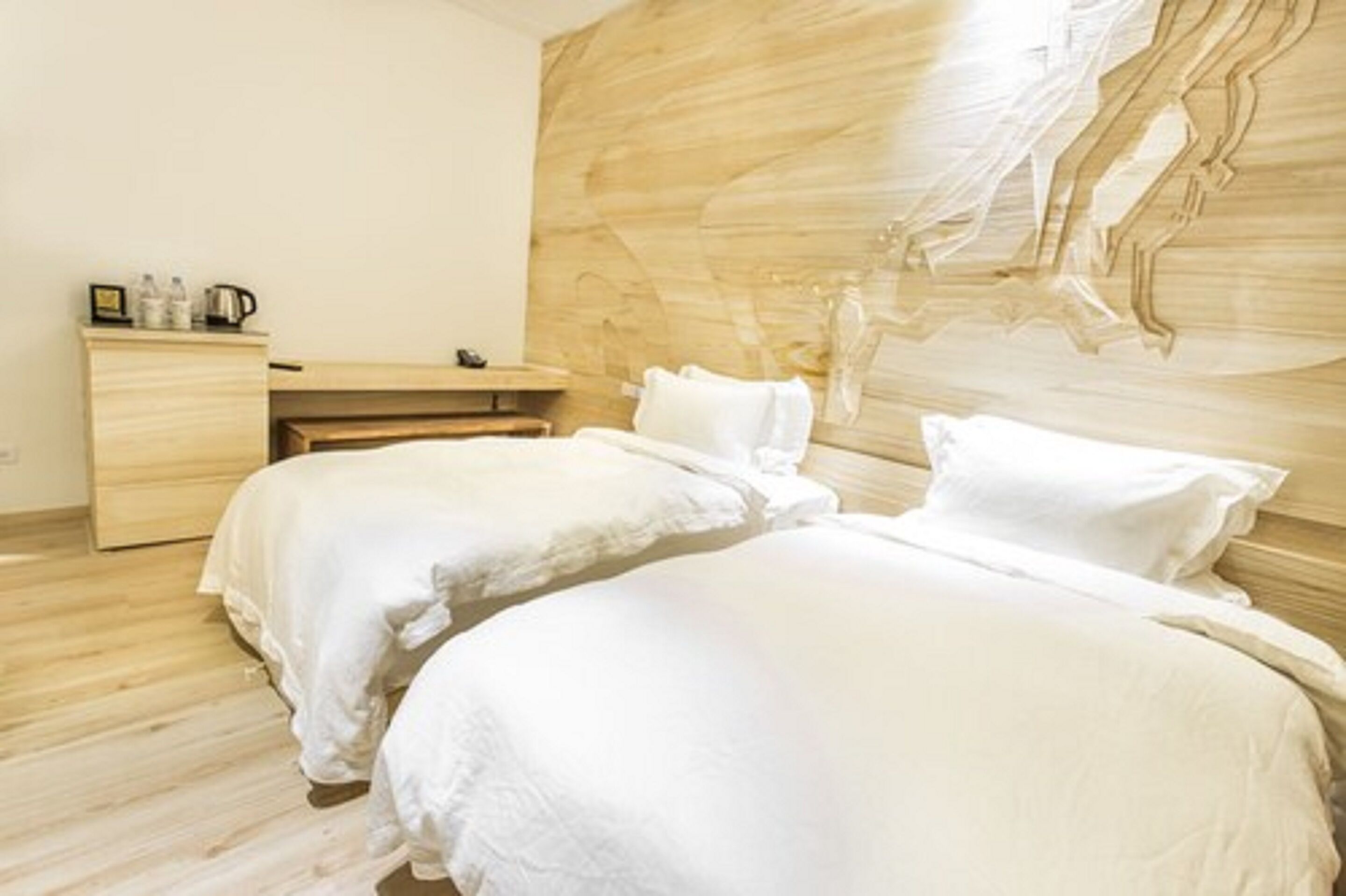 A bedroom with two beds, a wooden headboard, a small desk, and a nightstand.