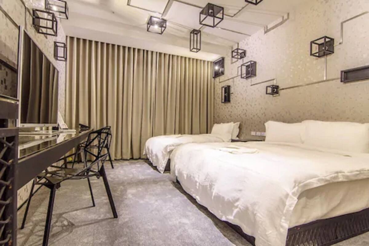 Habitación de hotel moderna con una cama grande, un escritorio con sillas y un fondo de cortinas.