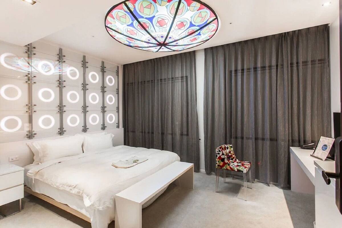 Un dormitorio moderno con cama, escritorio y silla.