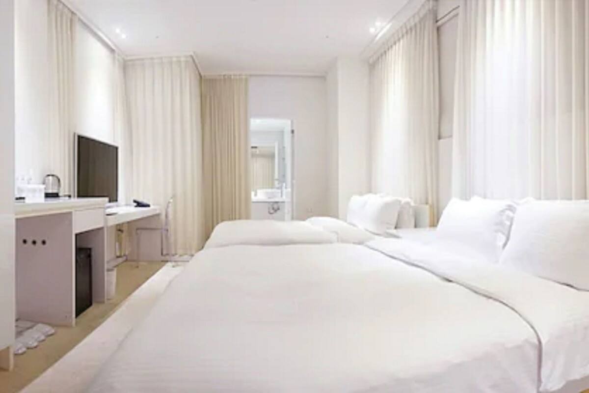 Habitación de hotel con una cama grande, un escritorio con silla, un televisor y un baño visible a través de una puerta abierta.
