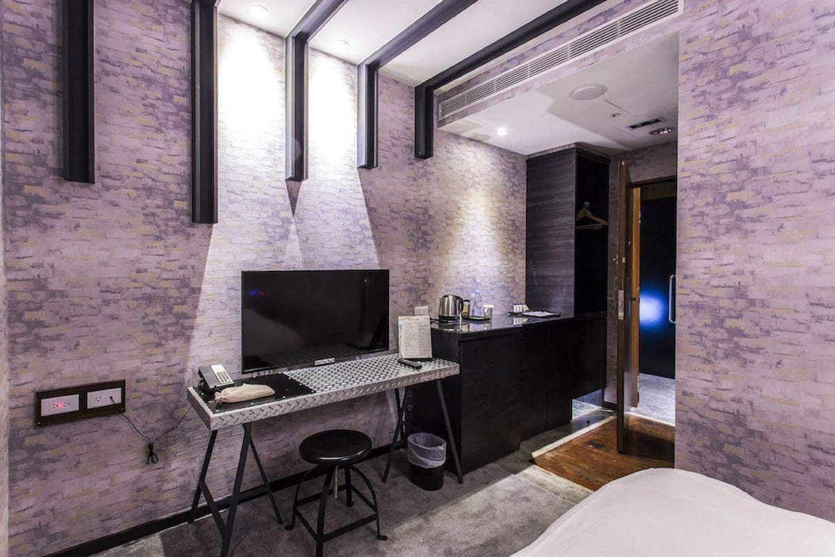 Una habitación moderna con escritorio, cama y una pequeña kitchenette.