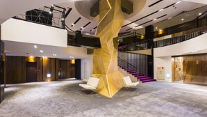 Un vestíbulo amplio con una escalera central, varias zonas de estar y un diseño moderno.