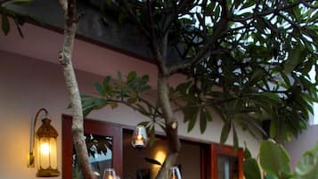 A dining table set outdoors with a tree in the center, surrounded by candles and a cozy atmosphere.