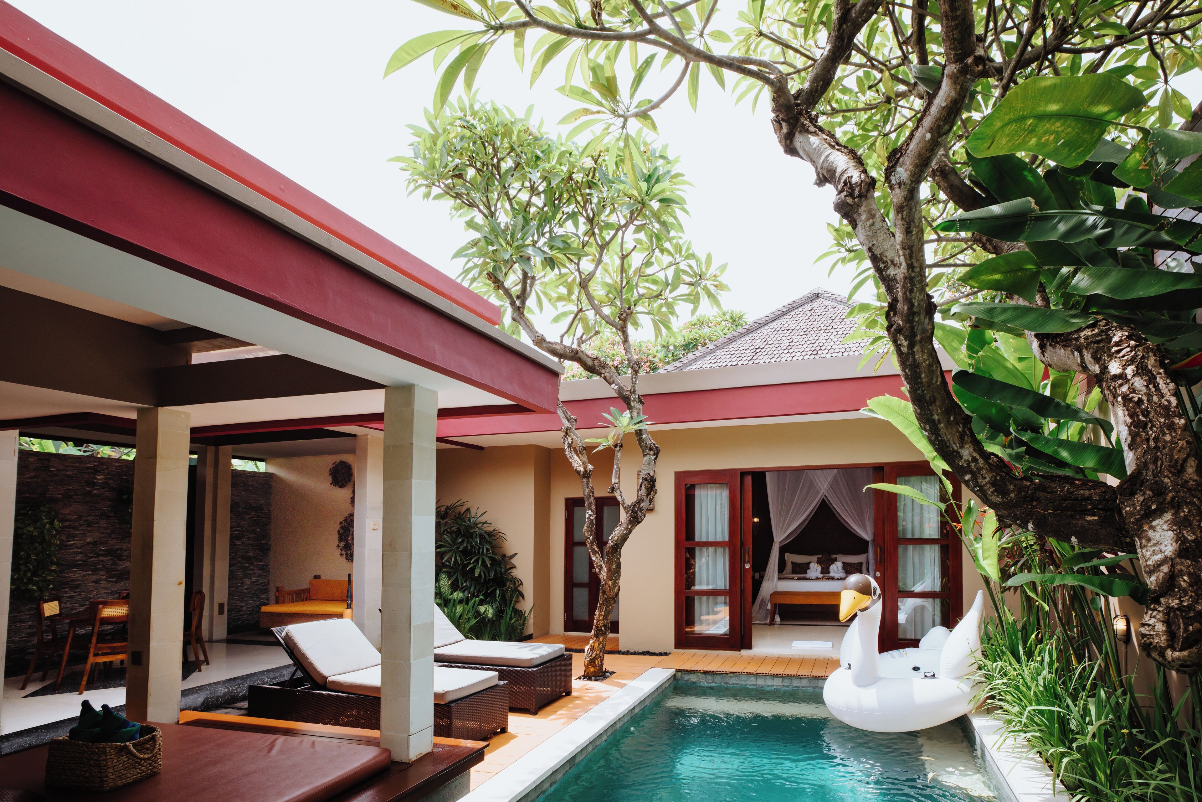 A pool area with a swan float, lounge chairs, and a covered seating area.
