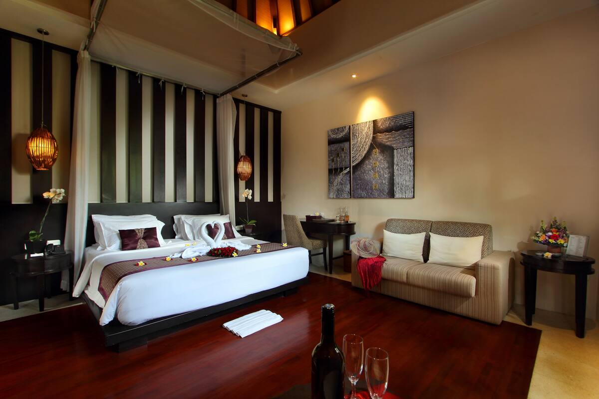 Quarto de hotel com uma cama grande, um sofá, uma mesa de jantar e um quadro na parede.