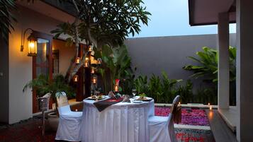 An outdoor dining area with a round table, chairs, and candles.
