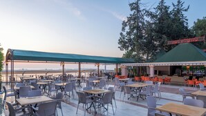 An outdoor patio area with tables and chairs, a covered seating area, and a view of the sea. - Lims Bona Dea Beach Hotel – All Inclusive (Kemer)