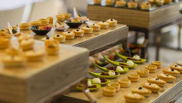 Una mesa de buffet con diversos alimentos, incluyendo mini pasteles y postres, dispuestos en tablas de madera.
