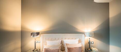 A neatly arranged bedroom with a tufted headboard, two bedside tables with lamps, and a bed with pillows.