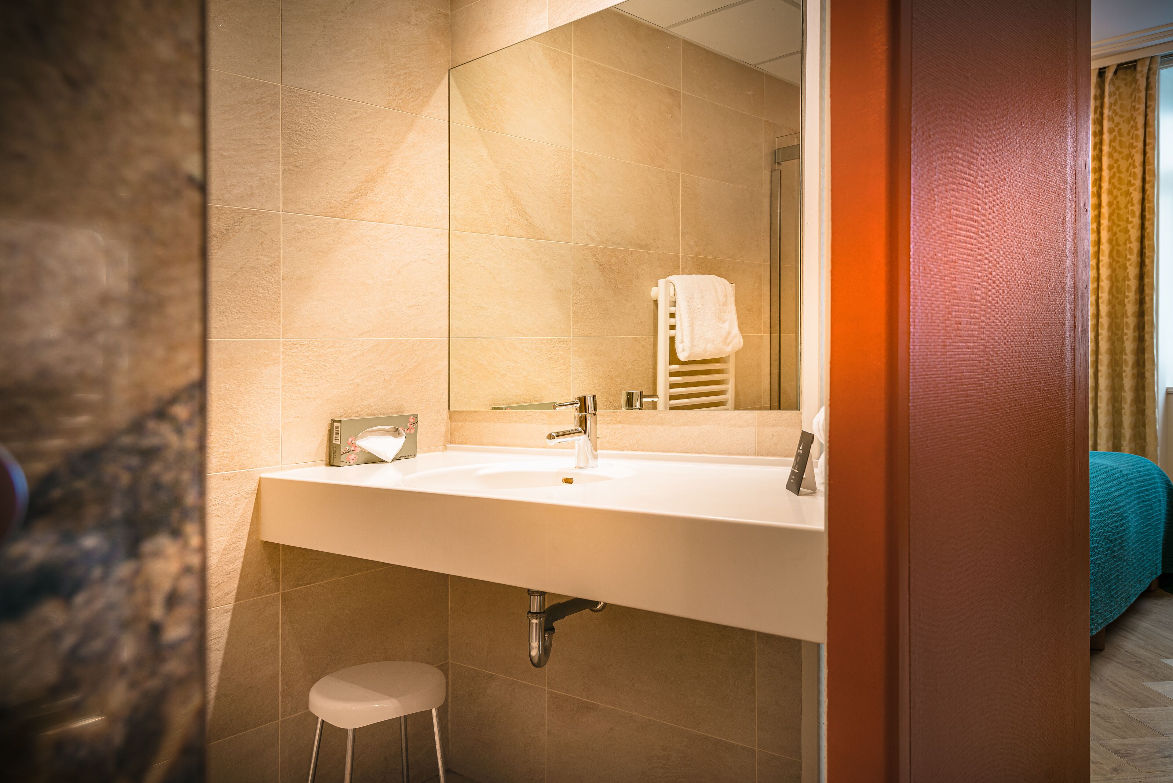 Ein Hotelbad mit einem großen Waschbecken, einem Spiegel und einem Handtuchhalter.