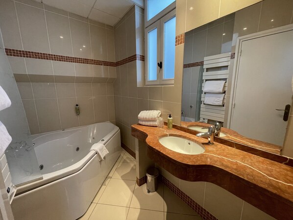 A modern bathroom with a bathtub, a sink, and a mirror.
