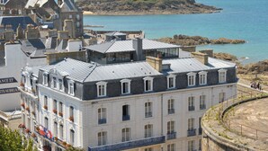 Un edificio histórico de varios pisos, con amplias ventanas y un balcón con barandillas.