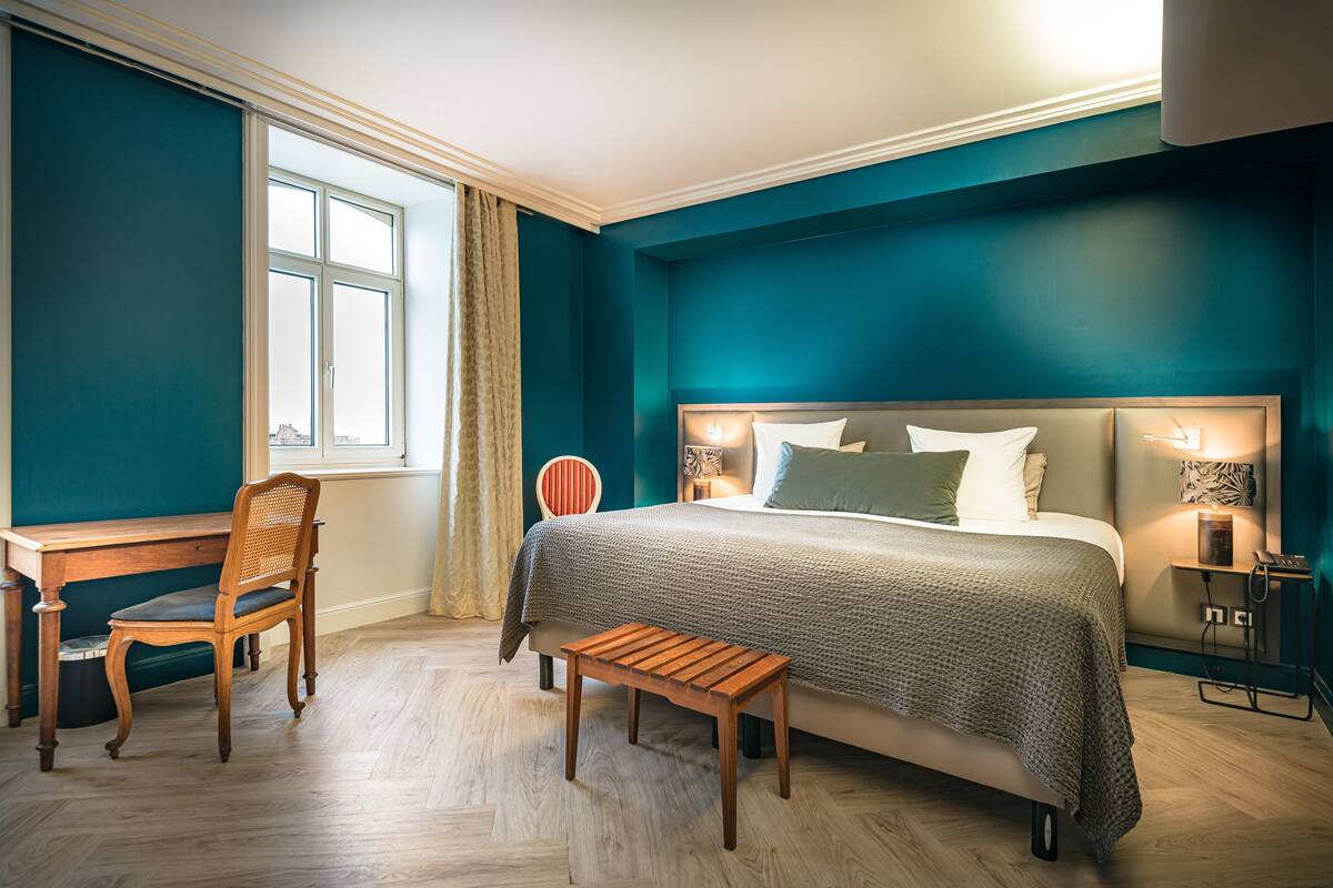 Une chambre à coucher avec un lit, un bureau, une chaise et un banc.