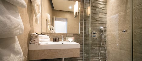 A modern bathroom with a glass-enclosed shower, a sink with a mirror above it, and a towel rack with folded towels.