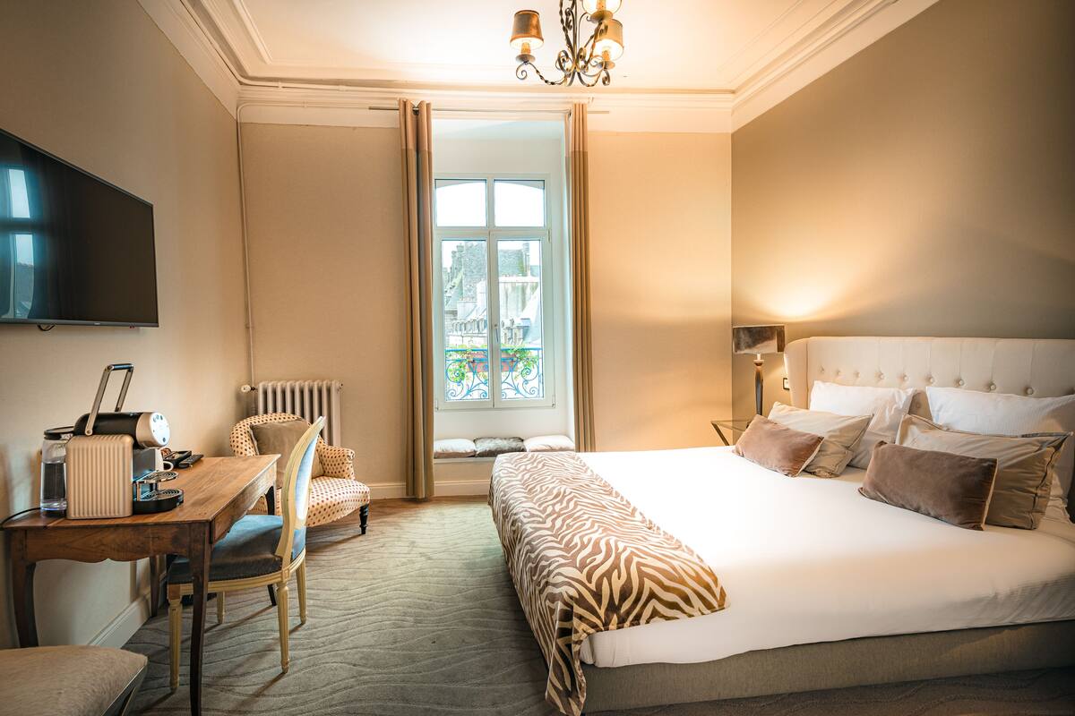 Une chambre d’hôtel avec un grand lit, un bureau avec un ordinateur, une chaise et un téléviseur.