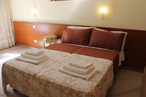 A neatly made bed with a floral bedspread and two pillows, a bedside table with a lamp, and a wooden headboard. - Le Terrazze del Vaticano (Rome)