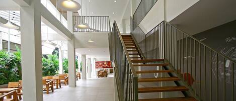 A spacious indoor area with a staircase, wooden flooring, and modern pendant lighting.