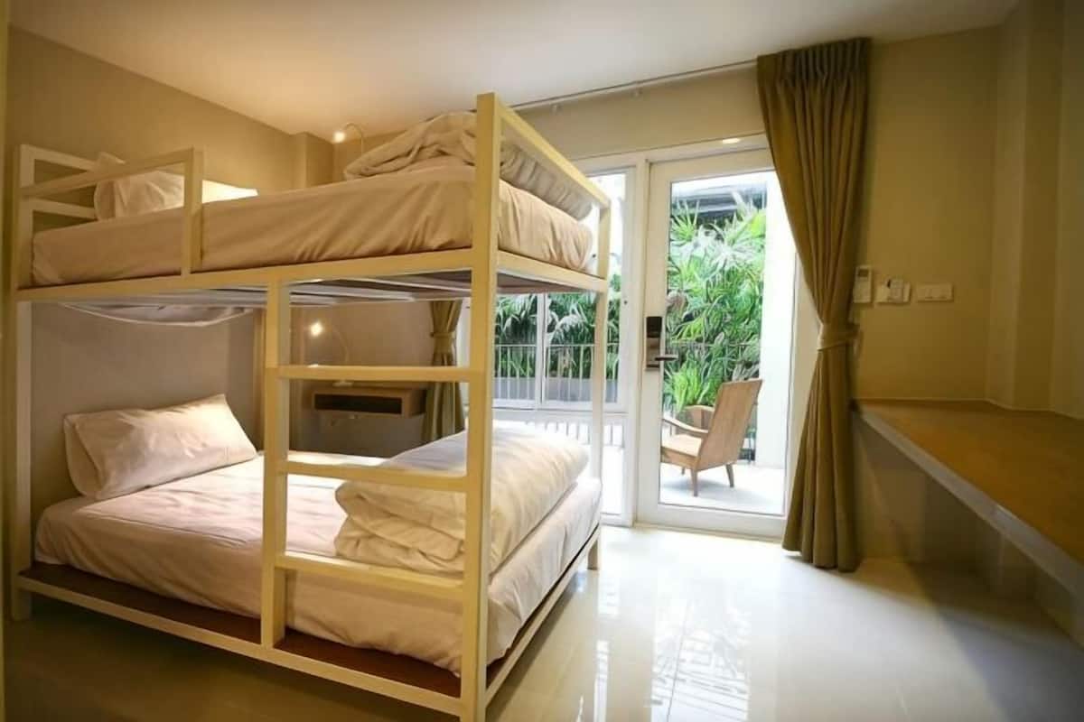 A bunk bed room with a balcony and a chair.