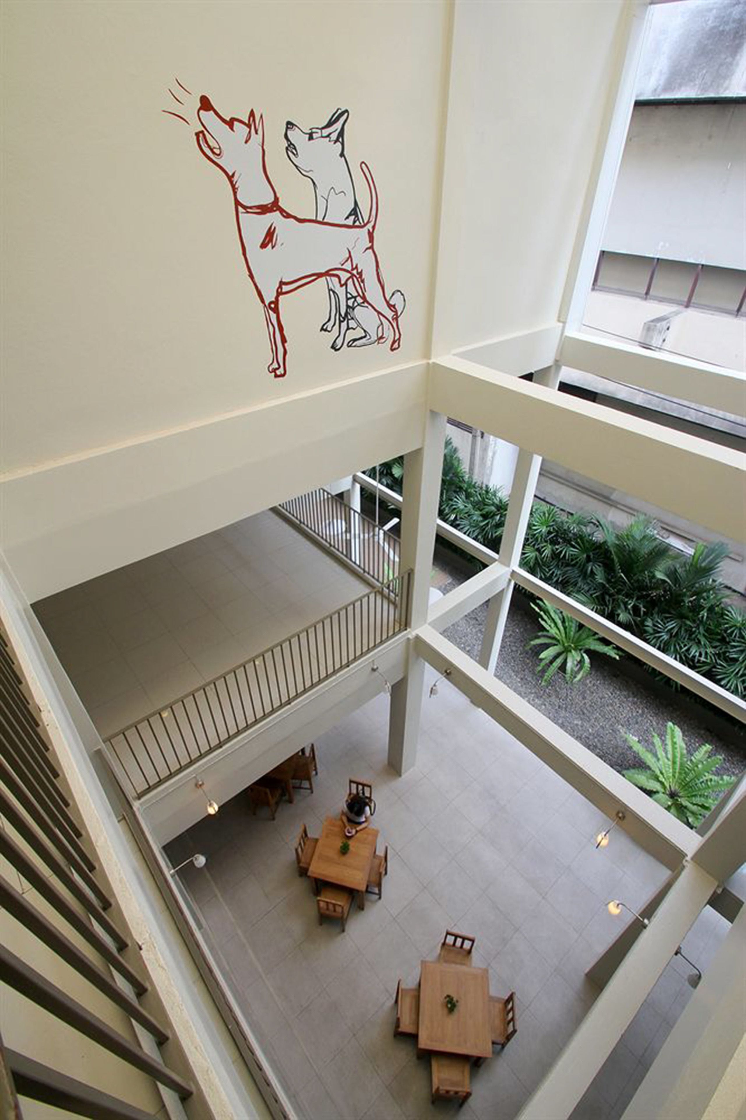 A multi-level interior with a dining area on the lower level and a view of a courtyard with plants.