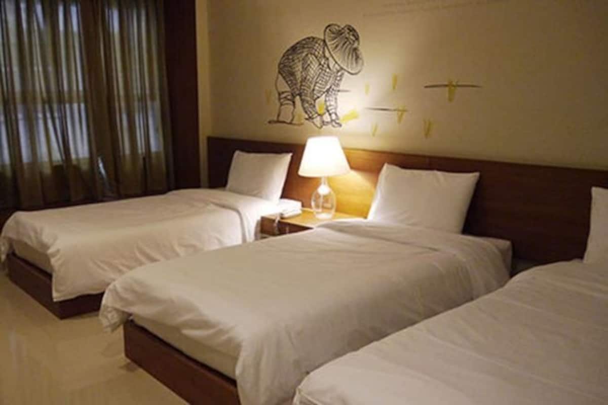 A hotel room with two single beds, a nightstand with a lamp, and a wall decoration of a bird.