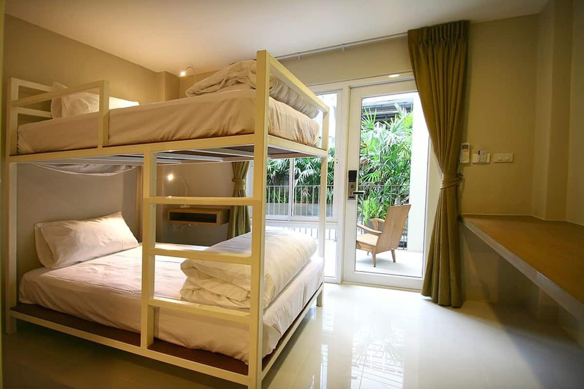 A bunk bed room with a balcony and a chair outside.