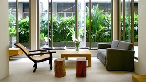 Ein modernes Wohnzimmer mit großen Fenstern, einem Deckenventilator und Blick auf üppiges Grün.