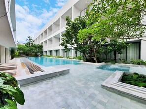 A modern hotel courtyard with a swimming pool, surrounded by lush greenery and a multi-story building. - CHERN Bangkok (Bangkok)