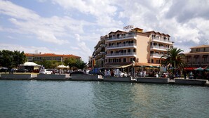 A hotel with multiple balconies, a waterfront view, and a pedestrian walkway along the water.