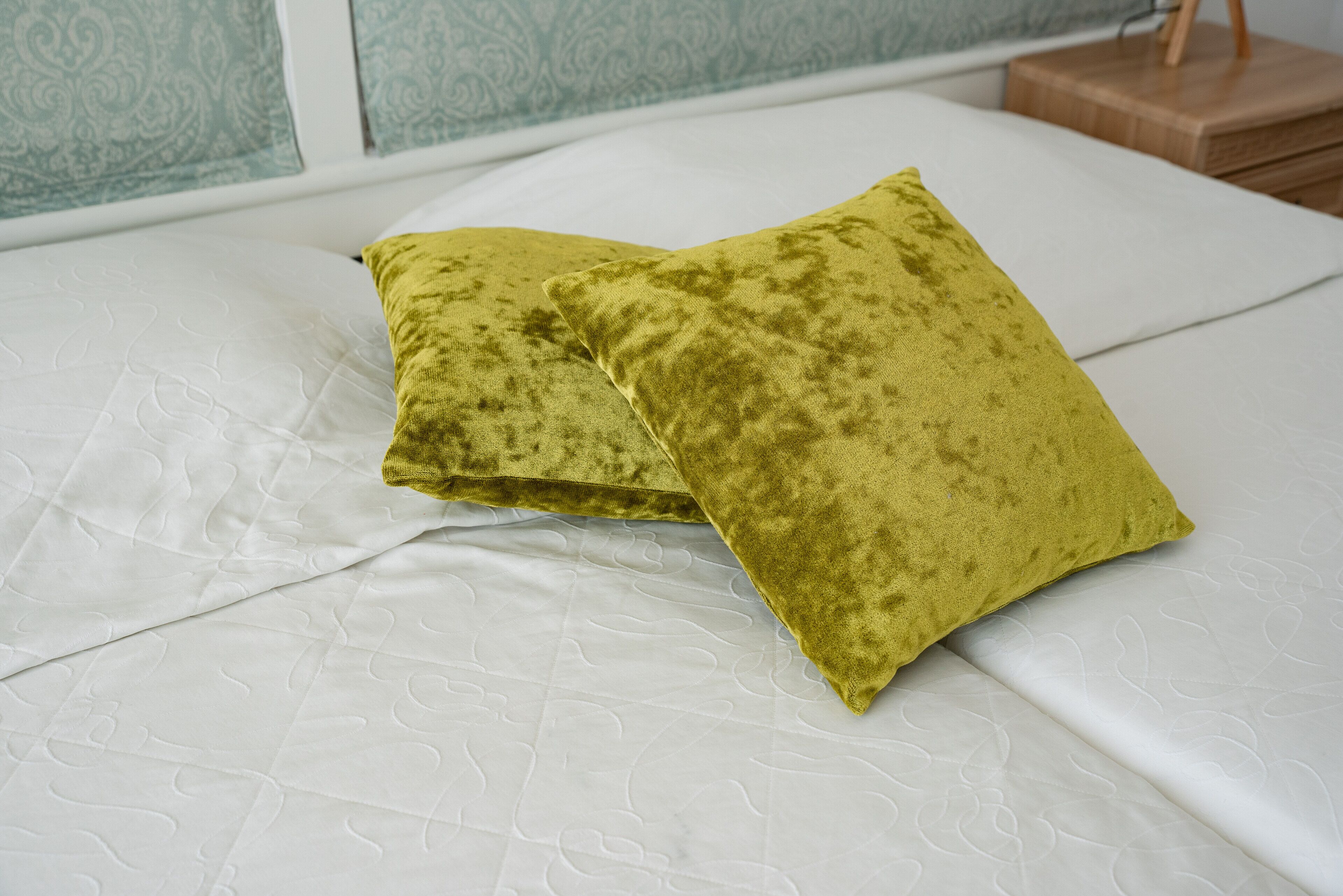 Ein Bett mit weißer Decke und zwei grünen Kissen.