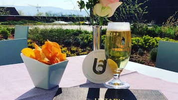 Una mesa con una jarra de cerveza, un bol de aperitivos y un arreglo floral.