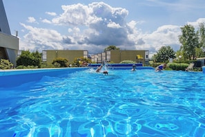 A swimming pool with clear blue water, surrounded by buildings and greenery. - Eden Resort & SPA (Mielno)