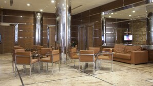 Eine moderne Lobby mit Ledersitzgelegenheiten, einem Fernseher und einem großen Spiegel.