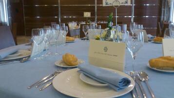 Una mesa de comedor dispuesta con platos, cubiertos y una servilleta doblada, con un cartel de número de mesa y un atril para el menú.