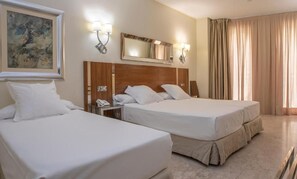 Habitación de hotel con dos camas, un espejo grande, luces fijadas a la pared y un cuadro.