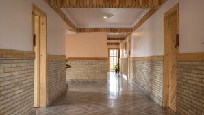 Un pasillo con paneles de madera y paredes de ladrillo, que conduce a una puerta al final.