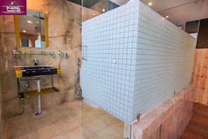 A modern bathroom with a marble sink, glass shelves, and a tiled shower enclosure.