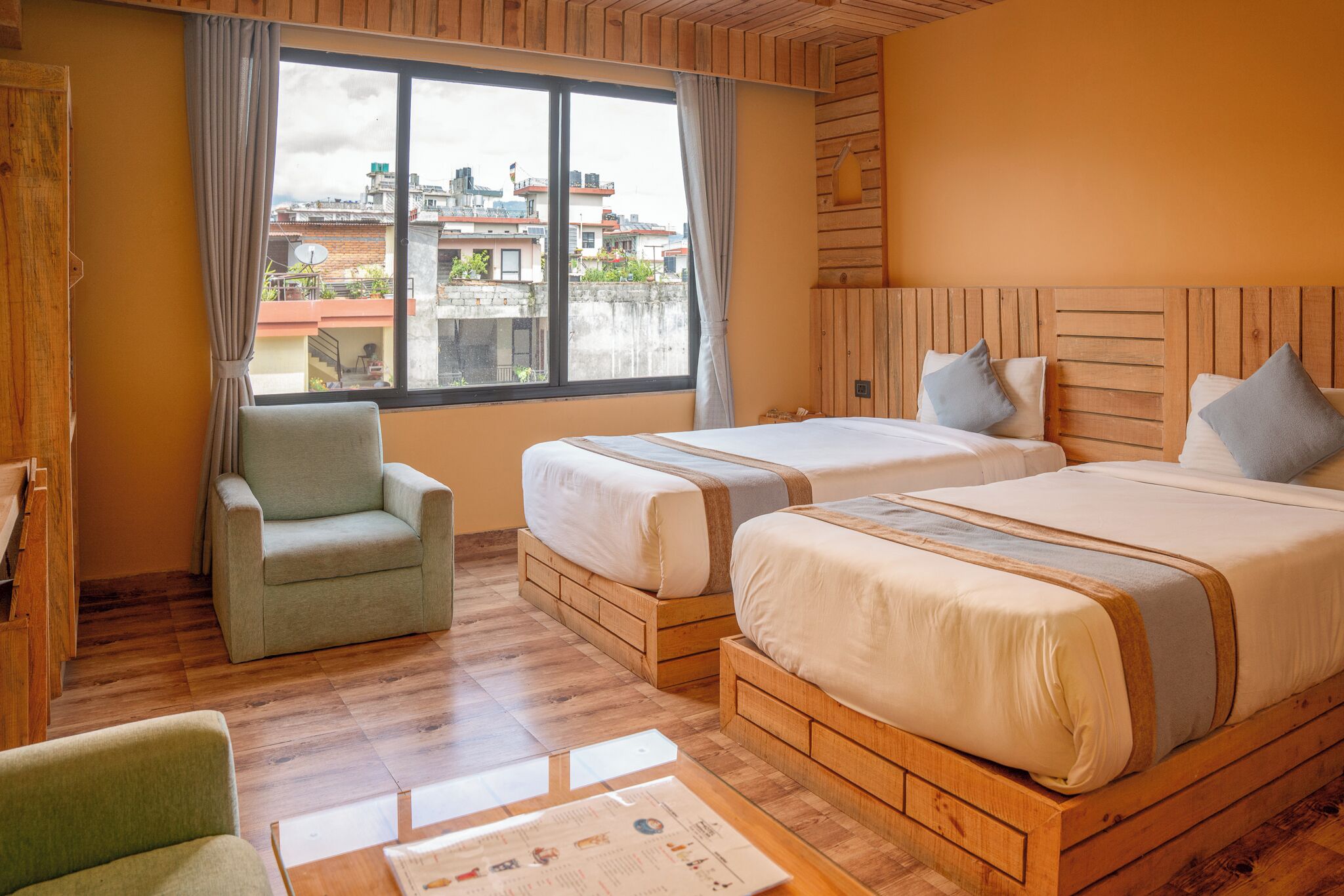 Een hotelkamer met twee bedden, een stoel en een houten vloer.