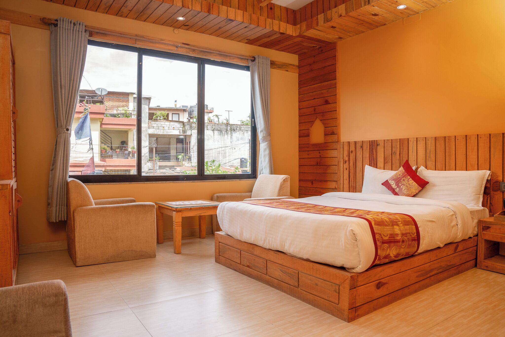 A bedroom with a wooden bed, a small table, a chair, and a window with curtains.