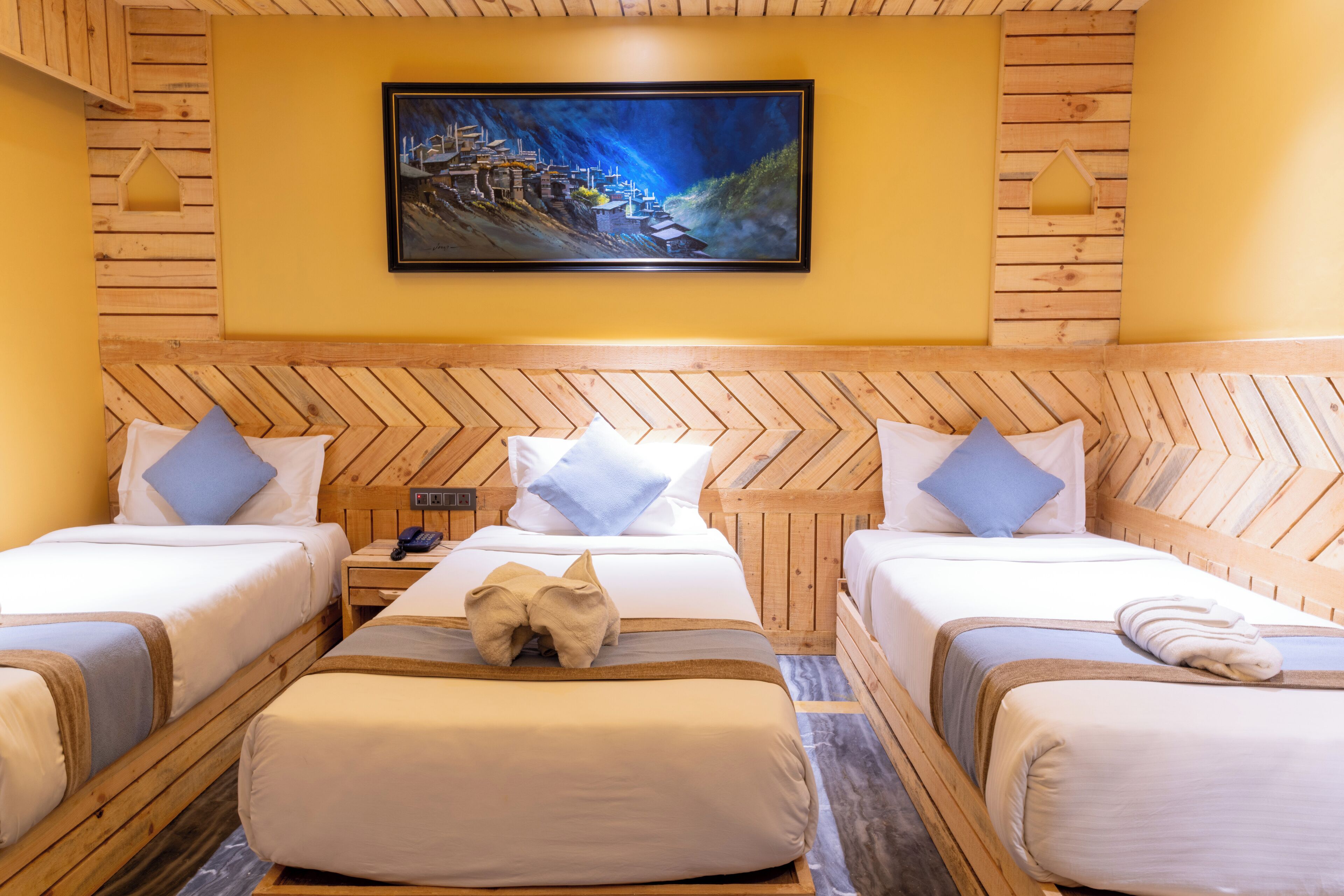 Habitación de hotel con dos camas, cabeceros de madera, un cuadro en la pared y una mesita de noche con un teléfono.