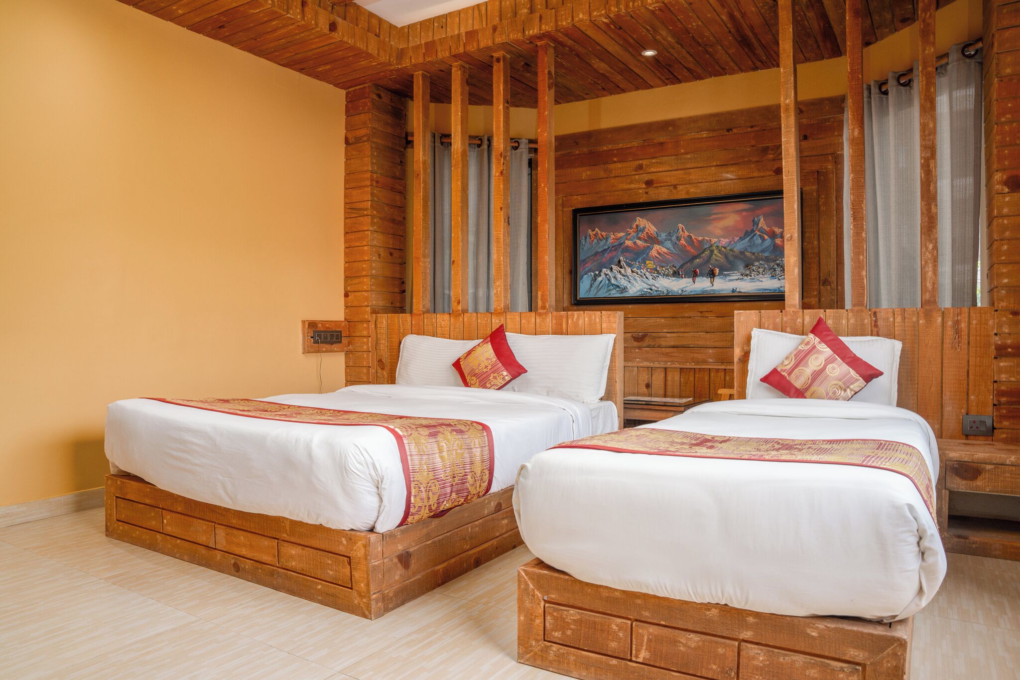 Una habitación de hotel con dos camas de madera, un cuadro grande de montañas en la pared y techo de madera.