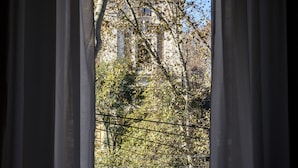 Vista a través de una ventana con un edificio y árboles al fondo.