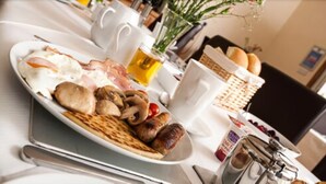 A breakfast plate with eggs, sausages, mushrooms, and toast. There are white mugs, a bottle of juice, and a basket of bread on the table. - Silverstrands Guest House (Inverness)