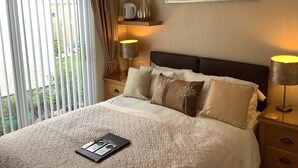 A neatly made bed with a patterned bedspread, a bedside table with a lamp, and a framed picture on the wall. - Silverstrands Guest House (Inverness)