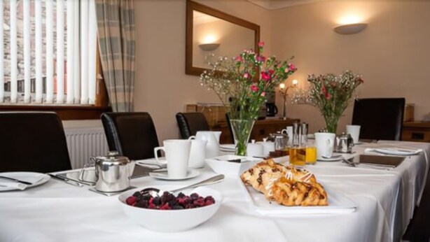 A dining table set with a bowl of berries, a plate of pastries, and various tableware. - Silverstrands Guest House (Inverness)