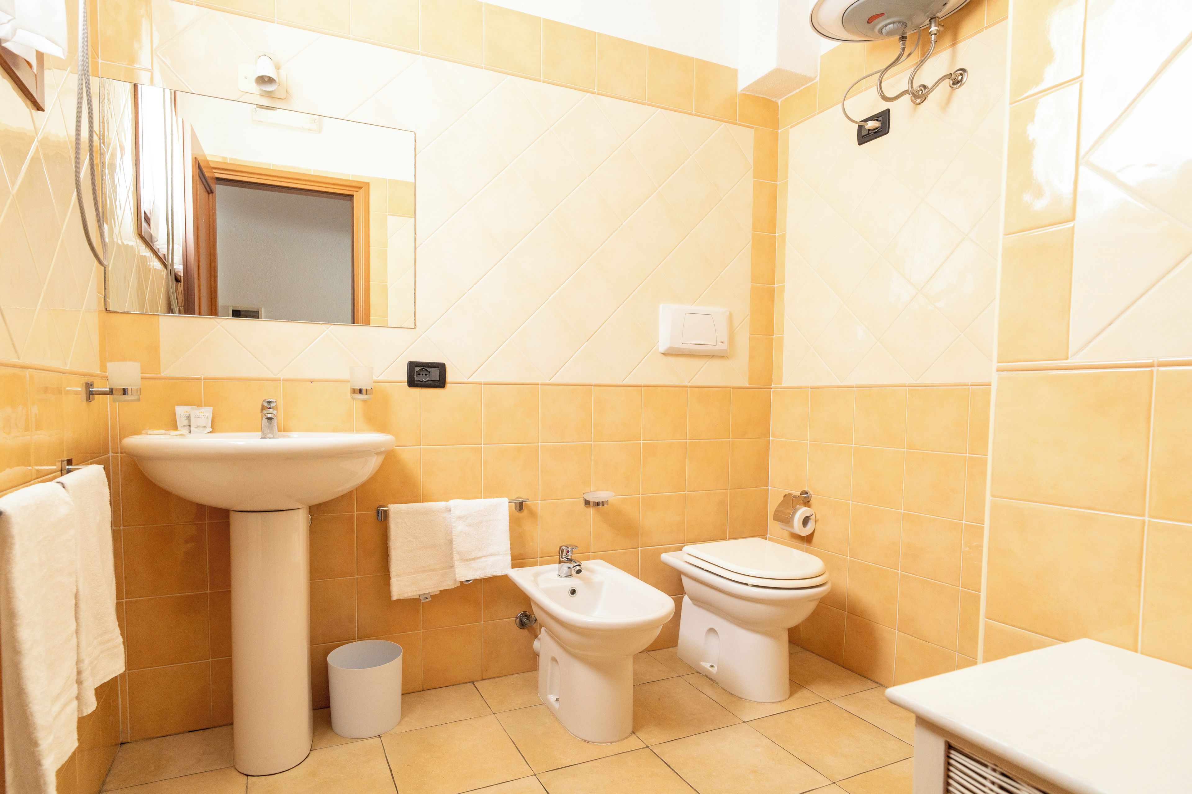 Un bagno con lavandino, bidet, WC e specchio.