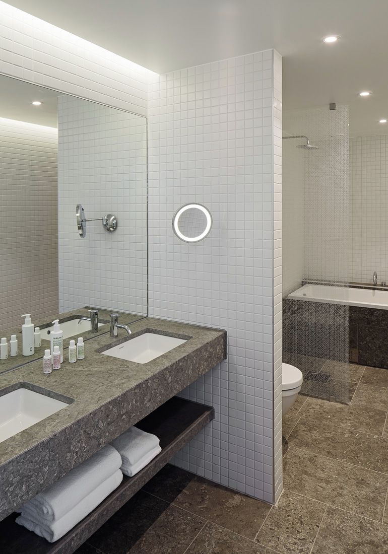 A modern bathroom with two sinks, a mirror, and a shower area.