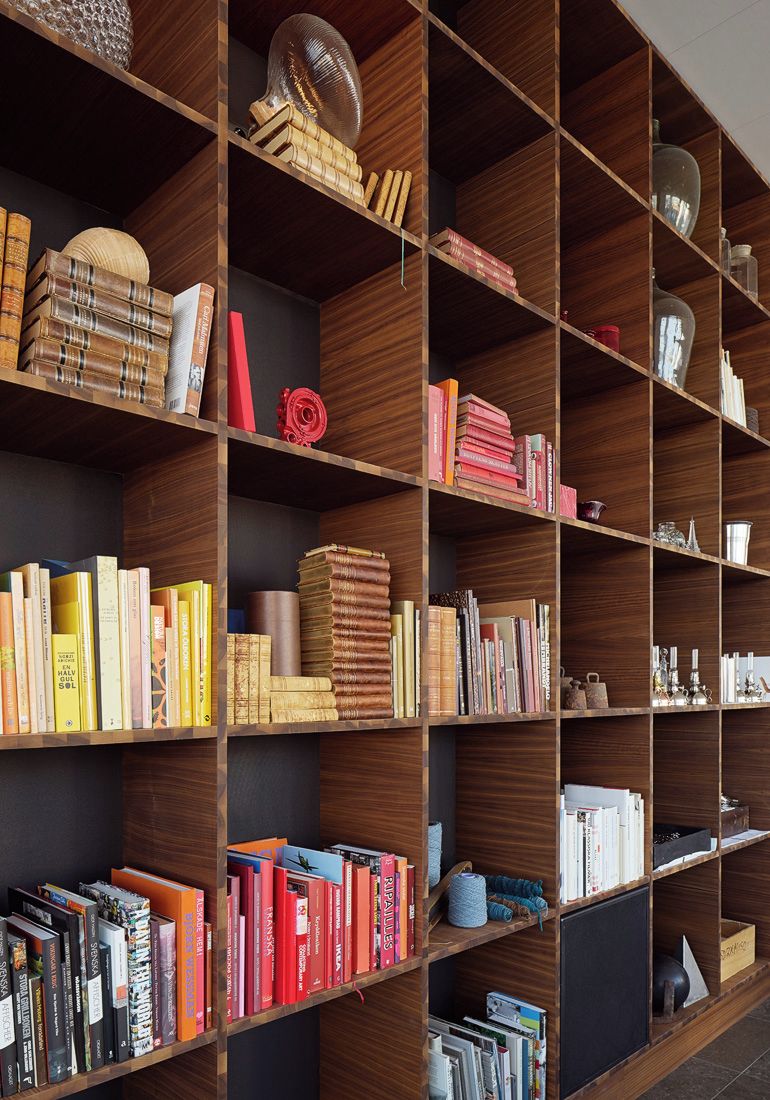 Una amplia estantería de madera llena de libros y objetos decorativos.