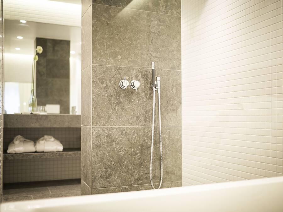 Une salle de bain moderne équipée d’une douche, d’un porte-serviettes et d’un lavabo.