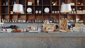 A bar area with shelves of bottles, a wooden counter with food items, and hanging lamps. - PM & Vänner Hotel (Växjö)