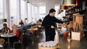 Un restaurante moderno con zona de bar, muebles de madera y vistas a la ciudad.